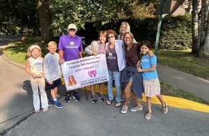 The Jaime Hawkins George Foundation holds a sign that congratulates their Charity Bib runners on raising $3,000